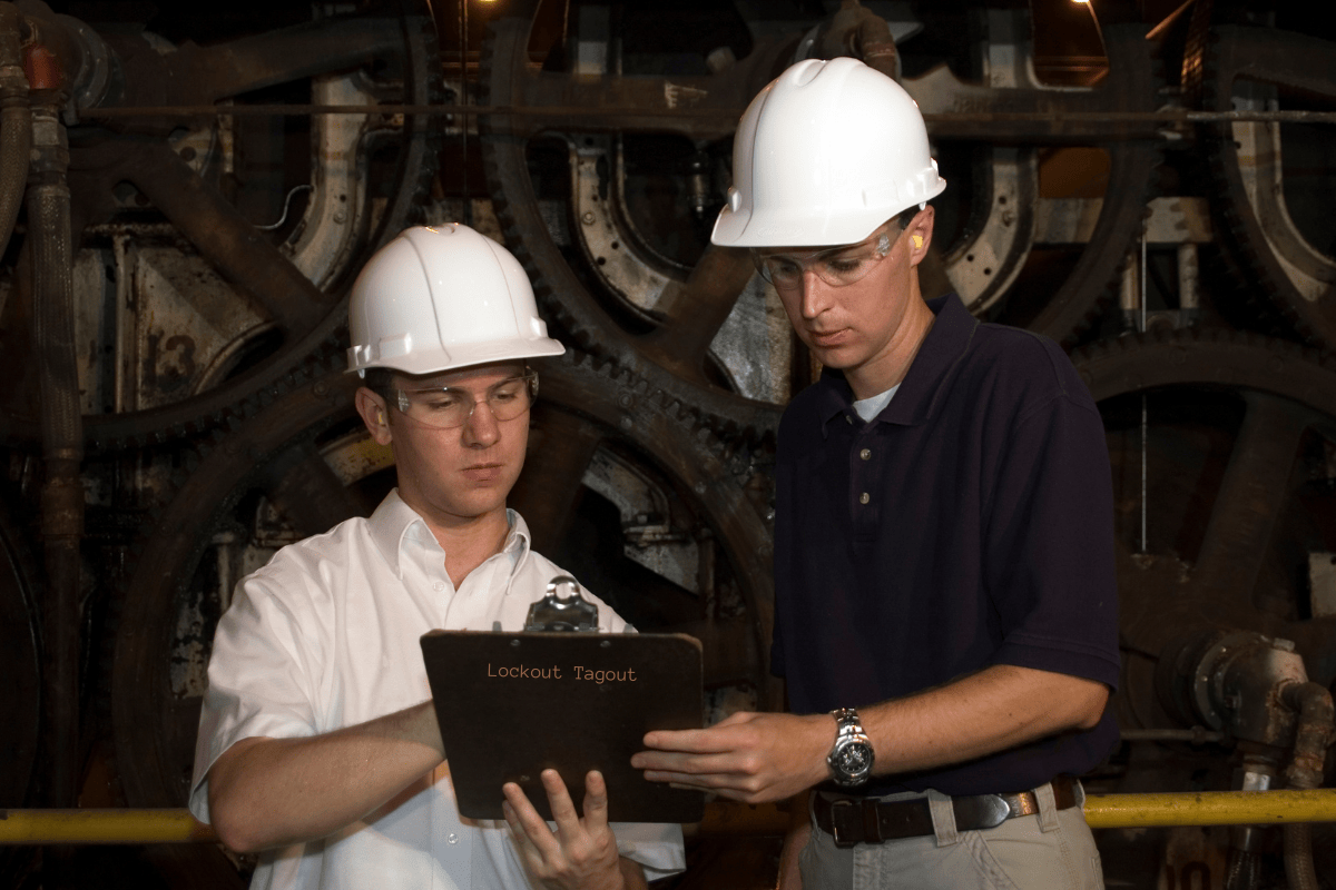 Lockout Tagout - OSHA 1910.147 - Men reviewing safety protocol by a machine